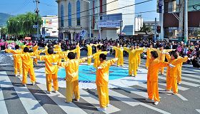 緊隨「天國樂團」後面的部份法輪功學員身著金黃色煉功服，向沿途觀眾展示功法。