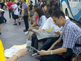 大陸遊客們接過法輪功真相材料，並當場閱讀起來