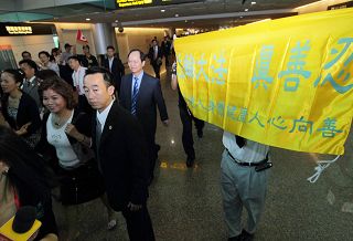 圖：黃華華所帶領的廣東團一出海關，即面對法輪功學員在桃園機場大廳打出「法輪大法　真善忍」、「停止迫害法輪功」等橫幅。