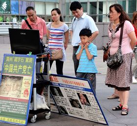 遊客聚精會神地看著法輪功真相影片