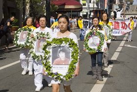 法輪功學員手持被迫害致死學員的照片