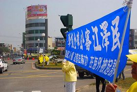 '陳雲林活動的耐斯王子飯店前，學員高舉法輪功真相橫幅'