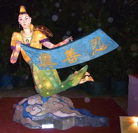 花燈「飛天」──身姿輕盈曼妙的仙女，以天衣彩帶飛揚，手上拿著「真、善、忍」旗子，腳踏彩雲來到人間，告訴世人修煉法輪大法的美好。