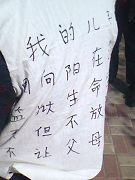 周向陽的母親身著白布大坎肩，上書：「我兒子生命垂危，港北監獄不讓父母見，我兒子是個好人。