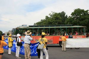 遊覽車上的遊客對遊行的法輪功學員招手致意