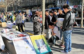 路人駐足觀看中共迫害民眾展板