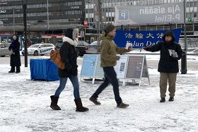 '行走匆忙的路人從法輪功學員手中接過真相資料'