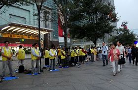 台灣法輪功學員長期在台灣各景點講真相及洪法，圖為大陸觀光客觀看法輪功學員在台北一零一大樓前煉功。