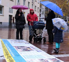 '民眾在雨中聽法輪功學員講真相'