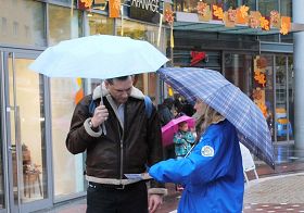 '民眾在雨中聽法輪功學員講真相'