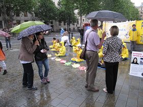 民眾冒雨觀看法輪功學員的功法演示