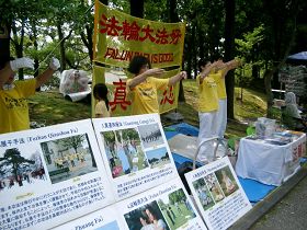 法輪功學員在稻澤市第十七屆夏季活動節展位上煉功