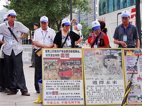 '遊客們聚集在展板前了解法輪功真相'