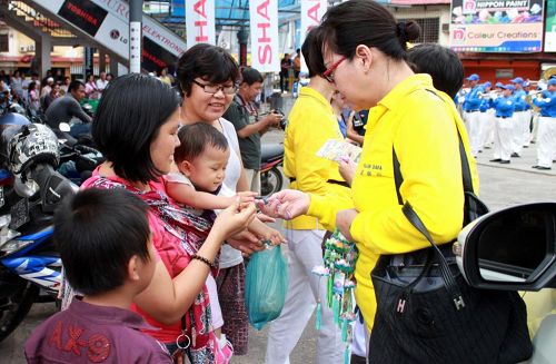 '民眾開心的向法輪功學員索取資料和蓮花。'