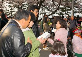 '來觀賞春花的遊客們，接過傳單在認真閱讀'