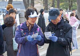 '來觀賞春花的遊客們，接過傳單在認真閱讀'