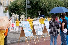 小雨中人們駐足觀看展板，了解真相