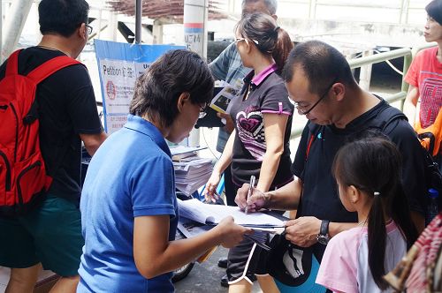 馬國吉膽島村口，當地民眾與遊客紛紛簽名，譴責中共活摘器官暴行。