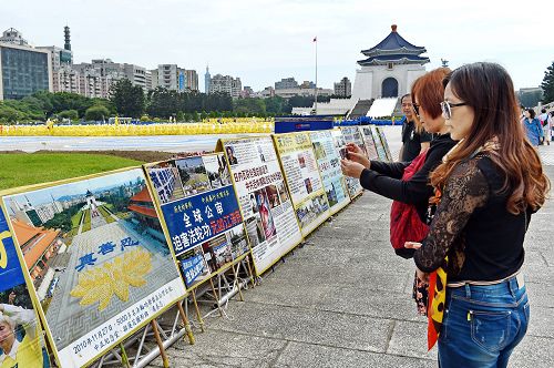 圖11-12：大陸遊客將法輪功學員排字盛況的真相展板內容照下，有的和展板合影，打算帶回國內給親友看。