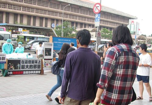 圖1.「中共活摘法輪功學員器官」模擬演示劇吸引旅客行人駐足關注。