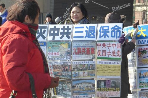 '退黨義工通過各種方式讓大陸遊客了解真相，包括手舉真相展板、播放真相廣播、發小冊子、掛橫幅等等，圖為義工王女士在向遊客展示真相展板。'