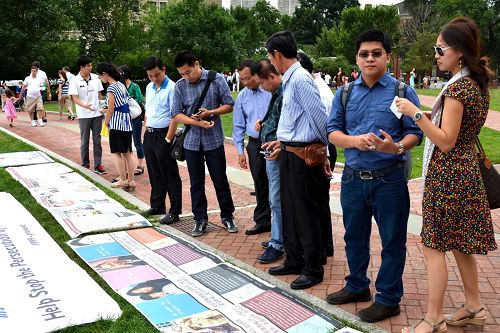 大批中、西方遊客認真閱讀講述法輪功真相的展板和圖片。