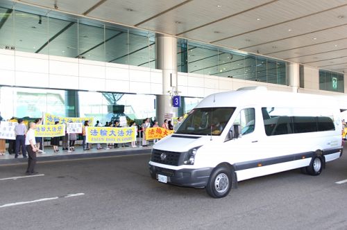 二十一日，當中共江西省委書記強衛（白色坐車）一到桃園機場接機大廳，便被法輪功學員當面告知：「你被告了！停止迫害法輪功。」