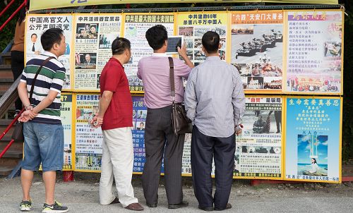 在西子灣「法輪大法好」的真相牆前，一位大陸遊客正用平板電腦快照存檔帶回去給親朋好友看。