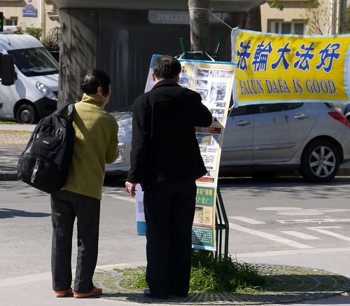 中國大陸遊客認真觀看巴黎埃菲爾鐵塔下退黨點的真相展版