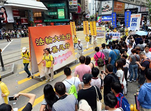 圖5-10：法輪功學員的遊行隊伍在天團樂團引領下，走過港島區鬧市街道，吸引港民及中西遊客駐足觀看及拍照。