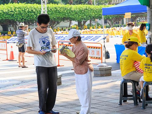 圖9：學員（右）給過往的民眾講述江澤民迫害法輪功的真相，民眾簽名聯署刑事舉報江澤民。