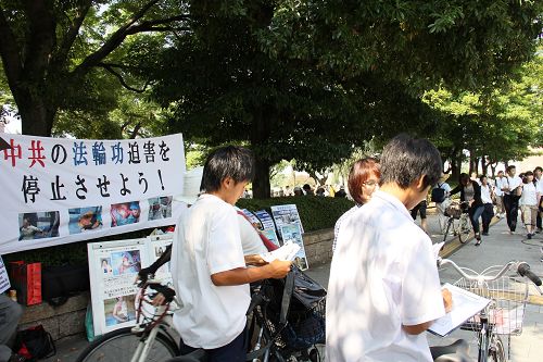 人們駐足觀看真相展板，或和學員交談了解真相