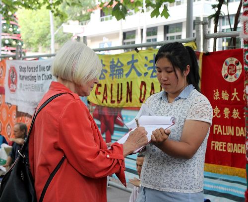 圖1-4：二零一五年十二月三十一日晚，在墨爾本市中心迎接新年到來的人們，駐足在法輪功學員徵簽的真相點，簽名舉報迫害元凶江澤民，呼籲制止中共迫害。