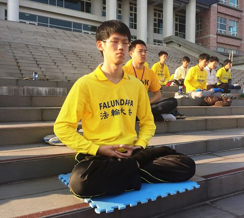 圖7. 虎科大研究生陳冠廷（前一）在環球科大校園和青年學子同修一起煉功。