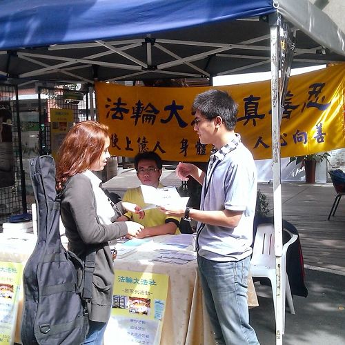 圖1. 師大學生卓廷威（右一）從小過敏體質，健康不佳，悲觀消極，幸於高二開始修煉法輪功，否極泰來，身心和人生觀都有意想不到的改善。圖為二零一四年十月師範大學校內舉辦法輪大法週，卓廷威向外籍交換生介紹法輪大法。