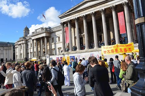 '圖7-9：二零一六年十月一日下午，法輪功學員在特拉法加（Trafalgar Sqare）北平台舉行集體煉功和講真相活動，吸引眾人目光。'