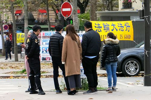 圖1-3：來巴黎旅遊的中國大陸遊客經過世界著名的埃菲爾鐵塔附近的法輪功真相點時，許多人駐足閱讀真相展板，了解真相。