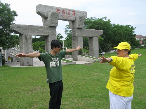 圖5：正好經過公園的楊先生看到現場有這麼多法輪功學員，很有興趣的走進了解，經過學員介紹後，他興起學煉的想法，於是詢問起煉功點，並且開始跟學員學煉起來。