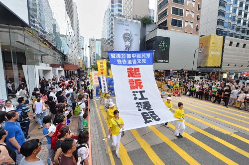 圖15-20：法輪功學員希望民眾了解真相，在遊行隊伍中打出了揭迫害、喚良知、啟善念、勸三退，及全球控告迫害元凶江澤民等橫幅。