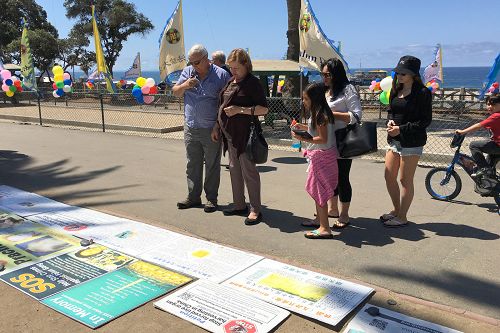 圖11：法輪功學員並在活動現場周圍擺放了真相展板，許多過往遊客駐足閱讀。