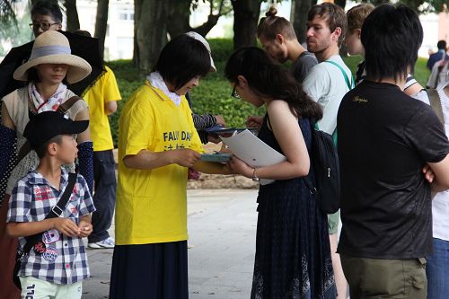 '圖1-2：日本法輪功學員在廣島核爆七十一週年日來到廣島和平公園，向來自世界各地的民眾揭露中共活摘法輪功學員器官的罪行，並徵集簽名聲援訴江。'