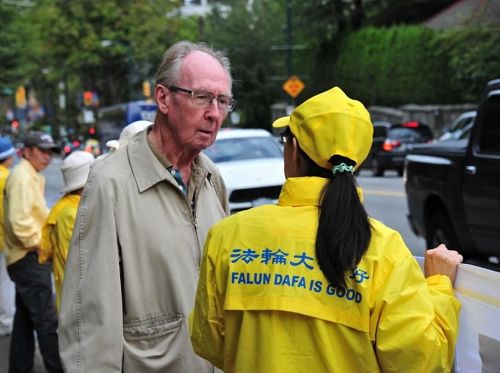 '圖4：市民Kennedy先生（左）經過活動地點，仔細聆聽現場的法輪功學員講述真相。'