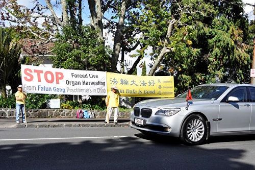 '圖2：3月28日下午，李克強一行離開新西蘭總督府，經過法輪功學員們的橫幅'