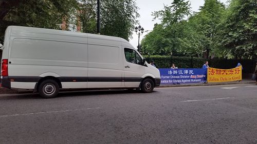 '圖2：愛爾蘭中使館調遣車輛遮擋法輪功學員橫幅，後被警方要求立即離開'