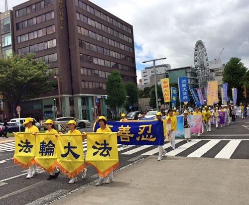 '圖1～2：八月五日（星期六），法輪功學員們從早上七點開始在愛知縣名古屋市中心的榮公園（Sakae Park）煉五套功法，之後在最繁華地區的榮（Sakae）舉辦遊行。遊行隊伍由精神抖擻的天國樂團引領，其後是打著「法輪大法好」、「真善忍」、「呼籲停止迫害法輪功」等橫幅的隊伍。'