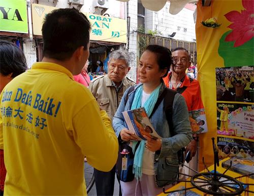 '圖2：遊客傾聽法輪功學員講真相'