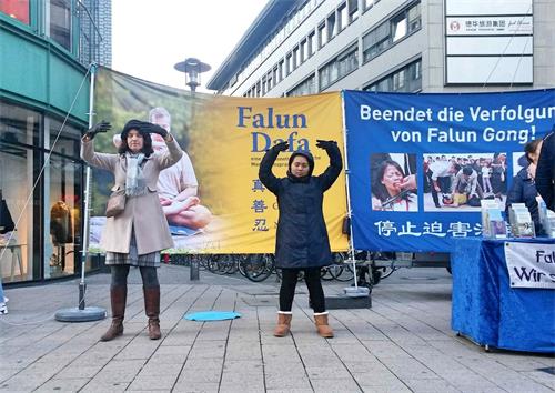 '圖1：二零一八年十一月三日，法輪功學員再次來到德國漢堡火車站附近的斯碧塔勒街（Spitalerstrasse）舉辦信息日活動。祥和的功法演示和揭露中共血腥迫害的真相橫幅形成了鮮明的對比。'