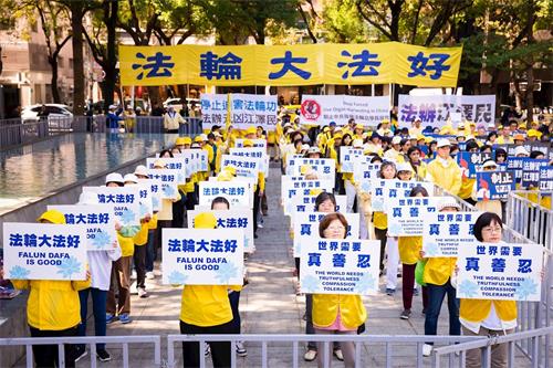 '圖2：法輪功學員手舉標語，傳遞「法輪大法好、停止迫害法輪功、法辦江澤民」等呼聲。'