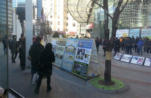 '圖4：來自中國大陸的一對青年男女走近真相展板，了解法輪功真相'