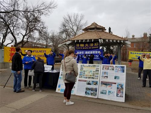 '圖1：市民被法輪功學員祥和的功法吸引，開始駐足觀看展板。'